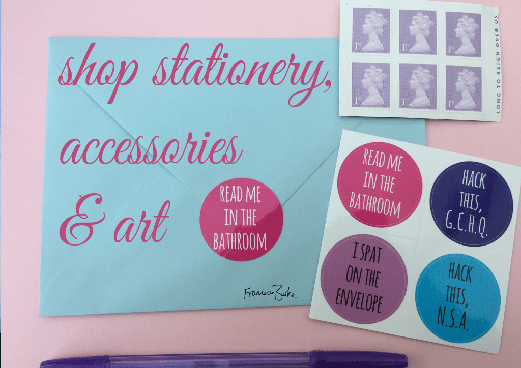 pink text 'shop stationery, accessories & art' on photograph of stickers, stamp and envelope with a pen